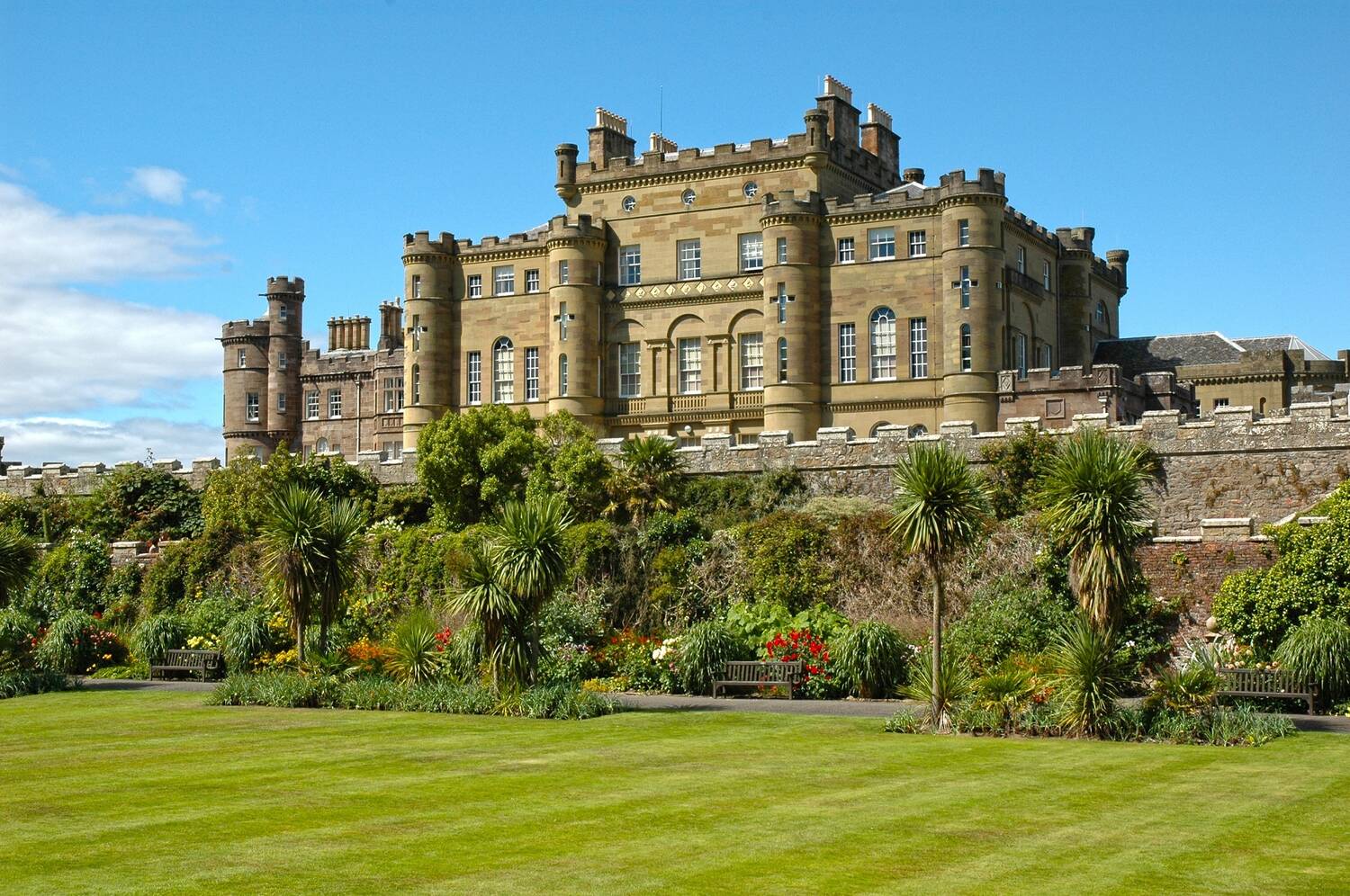 A view looking up and across a large manicured lawn to Culzean Castle. It is a bright sunny day.
