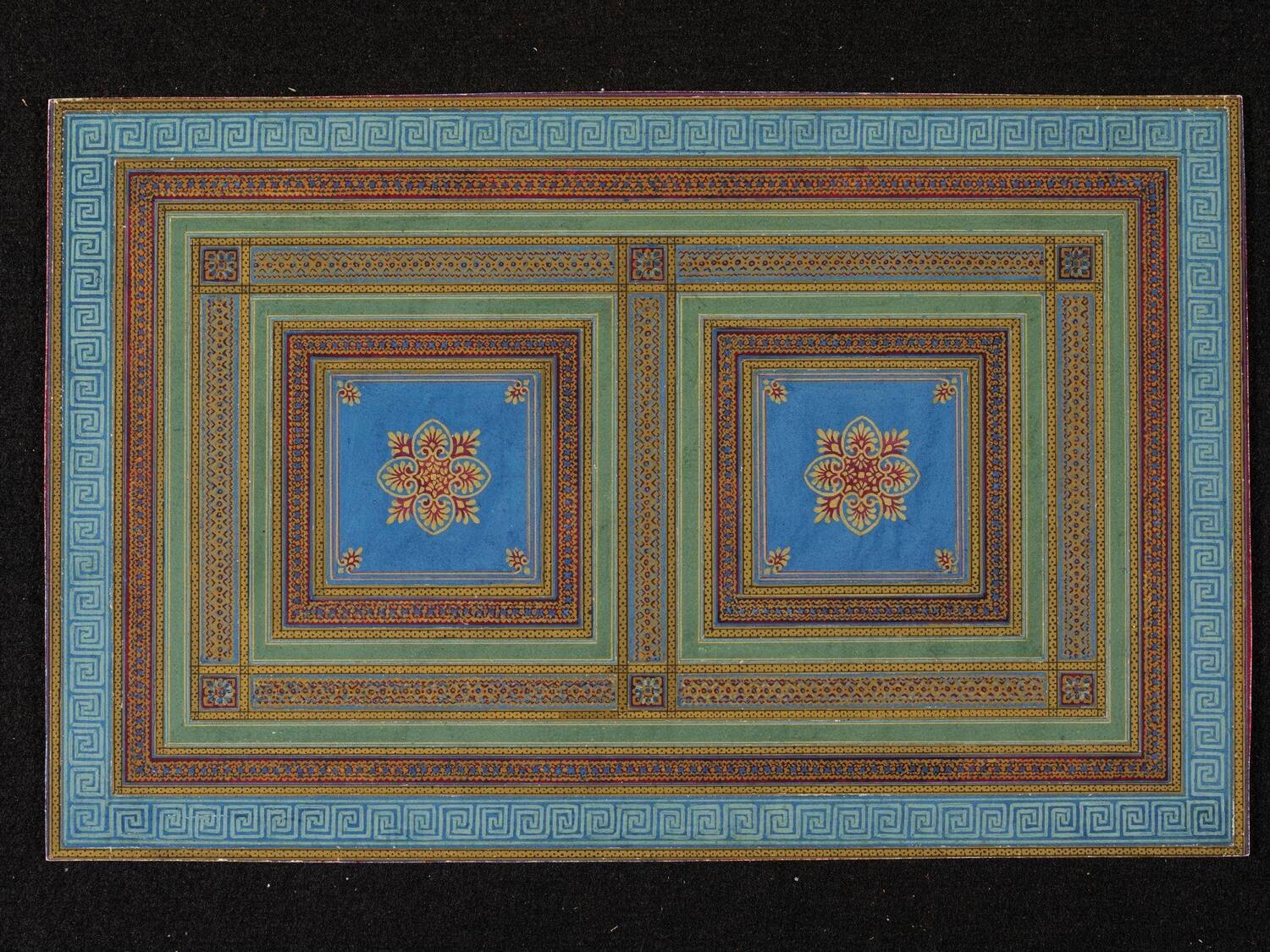 A large rectangular piece of carpet is displayed against a black background. The carpet features concentric squares of blue, green, yellow and red, some with classical patterns inside. At the centre are two blue squares with a floral design.