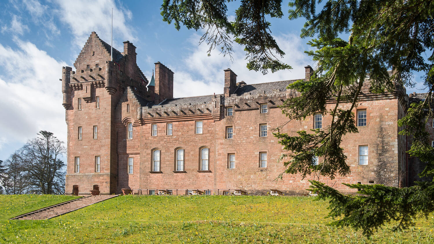 A view of the back of Brodick Castle, with pine branches in the foreground. 