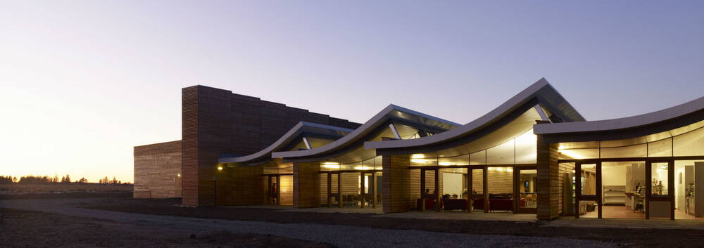 The stark outline of Culloden visitor centre seen at dusk, as the light fades outside. The centre is lit inside.