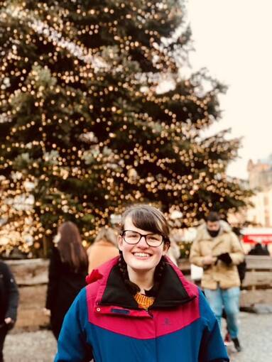 Woman stands in front of a Christmas tree