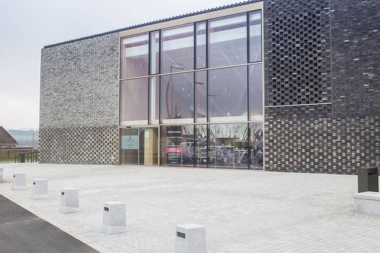 A close-up view of Bannockburn visitor centre, showing the grey walls that almost resemble chainmail. There is a very large plate glass window above the entrance doors.