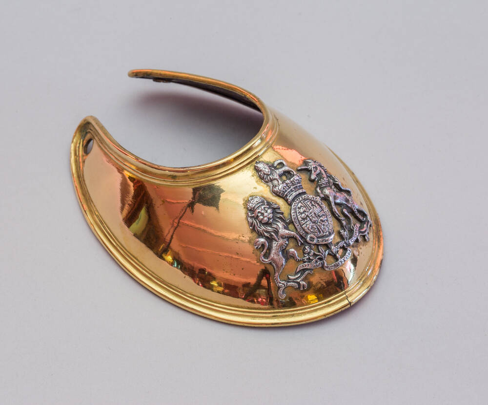 A large gilt necklace-type piece, with an embossed crest surrounded by a lion and unicorn.