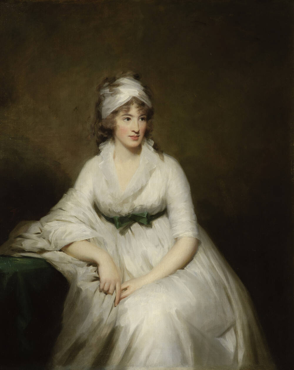 A portrait of Isabella Macleod. She is shown seated, resting one arm on her chair. She wears a billowing white dress, tied at the waist with a green sash. She has a white hair wrap, with her long brown hair falling from it.