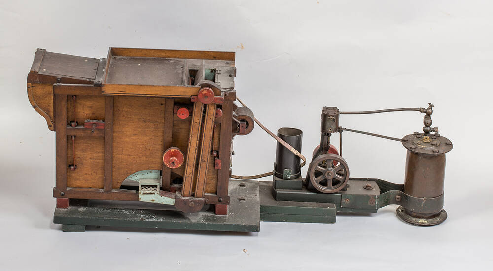 A wooden and metal model of a steam-powered threshing machine