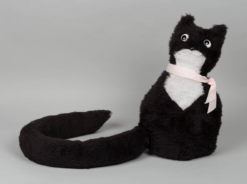 A black and white cat-shaped doorstop with a pink ribbon as a collar, and a detachable tail!