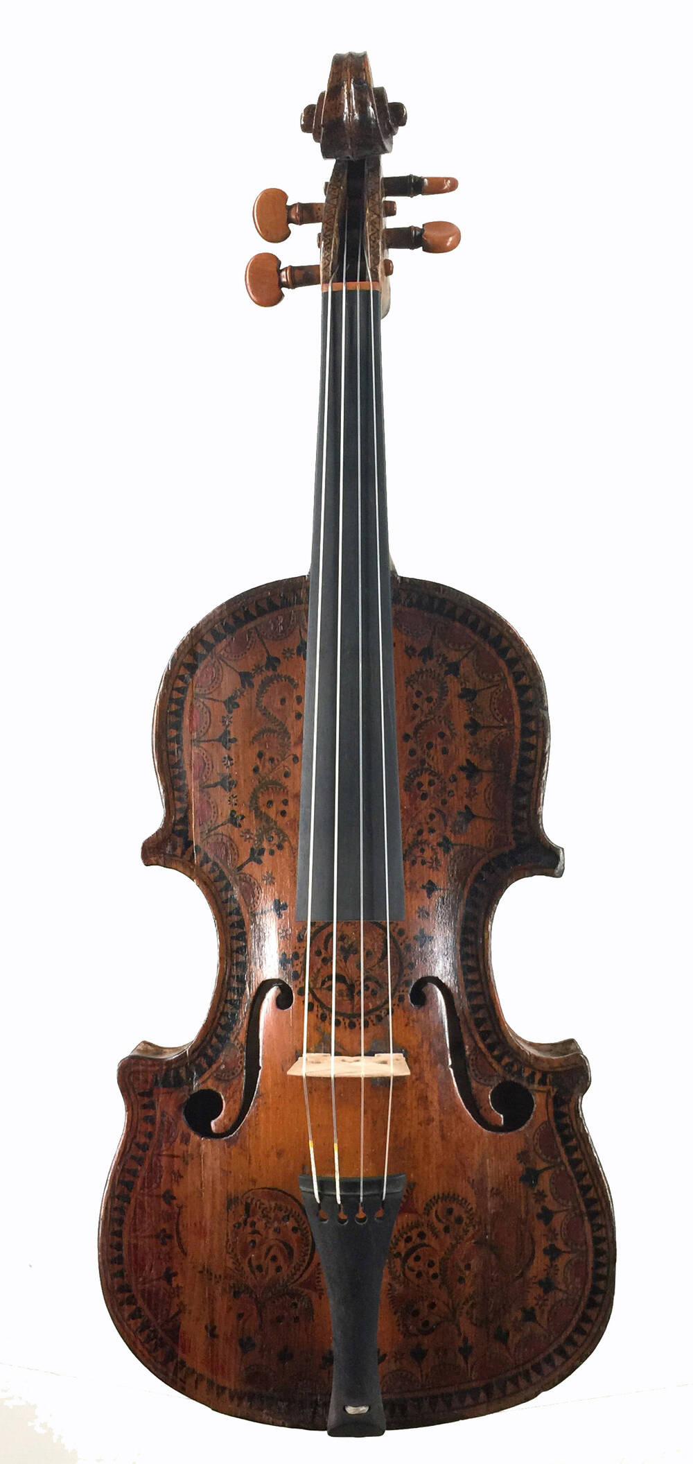 A fiddle is displayed face on, with the pegs at the top. The body is beautifully carved with floral images and decorative swirls.