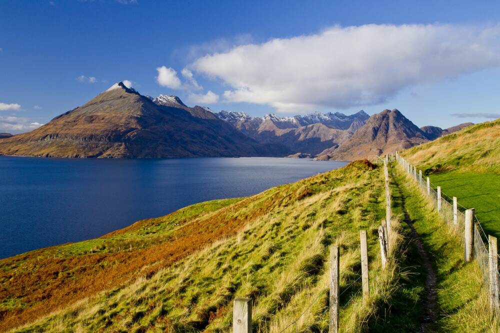 A fenced path runs beside Loch Scavaig, with mountains in the background.