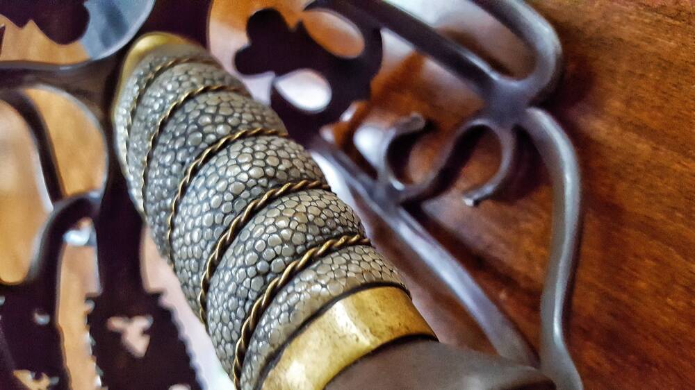 Handle of a broadsword covered with sharkskin and banded with gold wire several times.