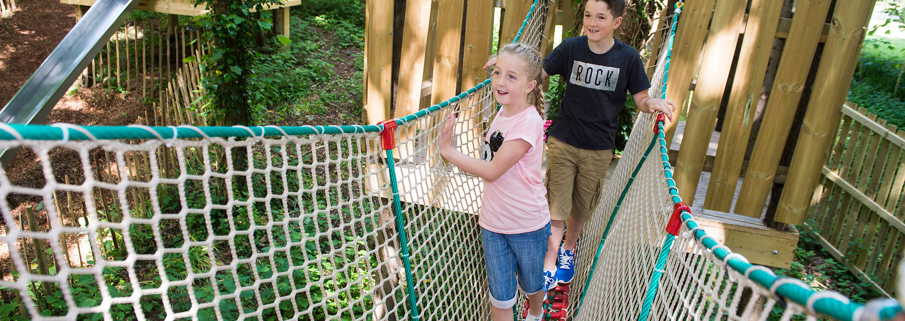 Children walking along a net at Culzean’s wild woodland play park