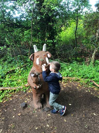 A small boy plays with the Gruffalo statue at Culzean Castle