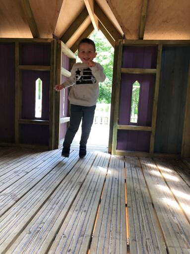 A young child runs through a wooden treehouse, in the play park at Culzean