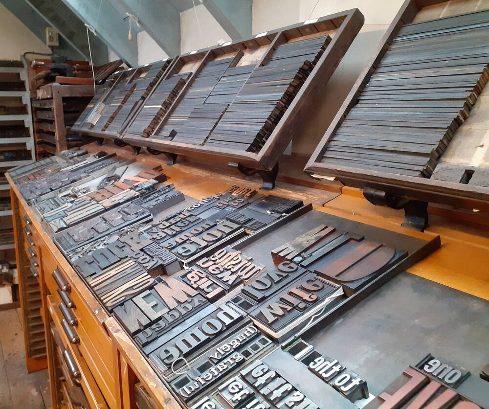 A view of multiple printing blocks, letters and shapes in wooden trays and drawers.