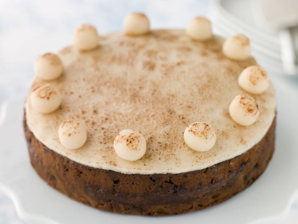 A simnel cake, showing a round fruit cake topped with a layer of marzipan and 11 marzipan balls around the edge.