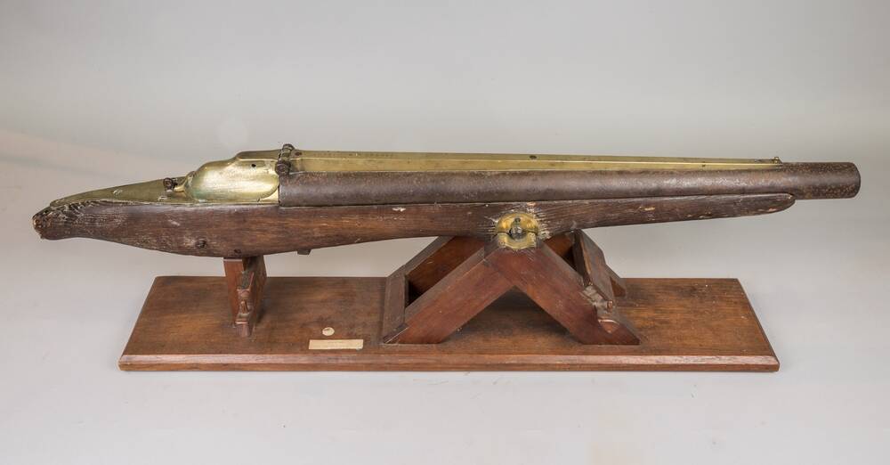 A harpoon gun resting on a wooden mount.