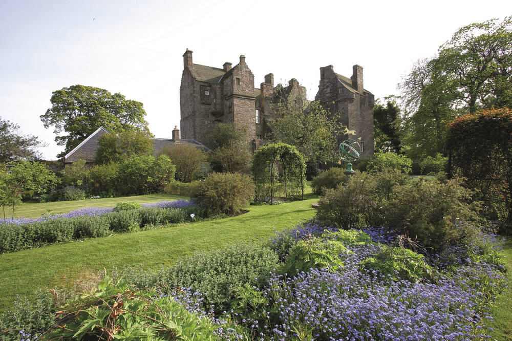 A view of Kellie Castle in Fife, with the flower-filled gardens in the foreground.