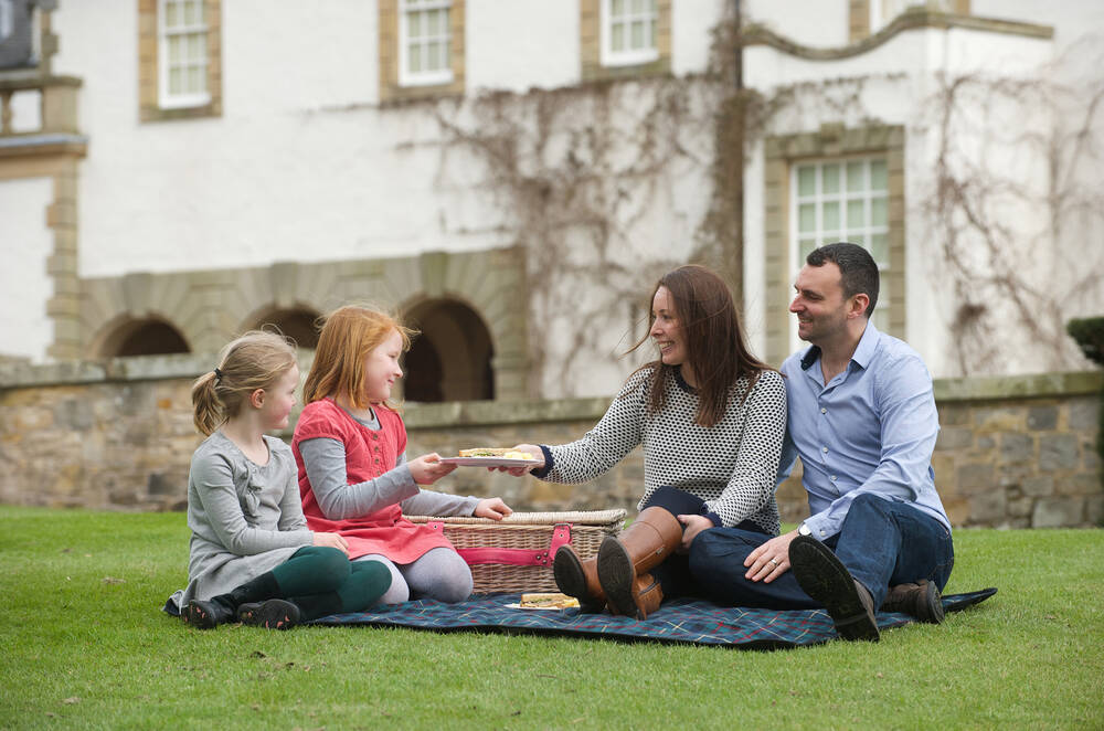 A family enjoying a picnic on the lawn at Hill of Tarvit