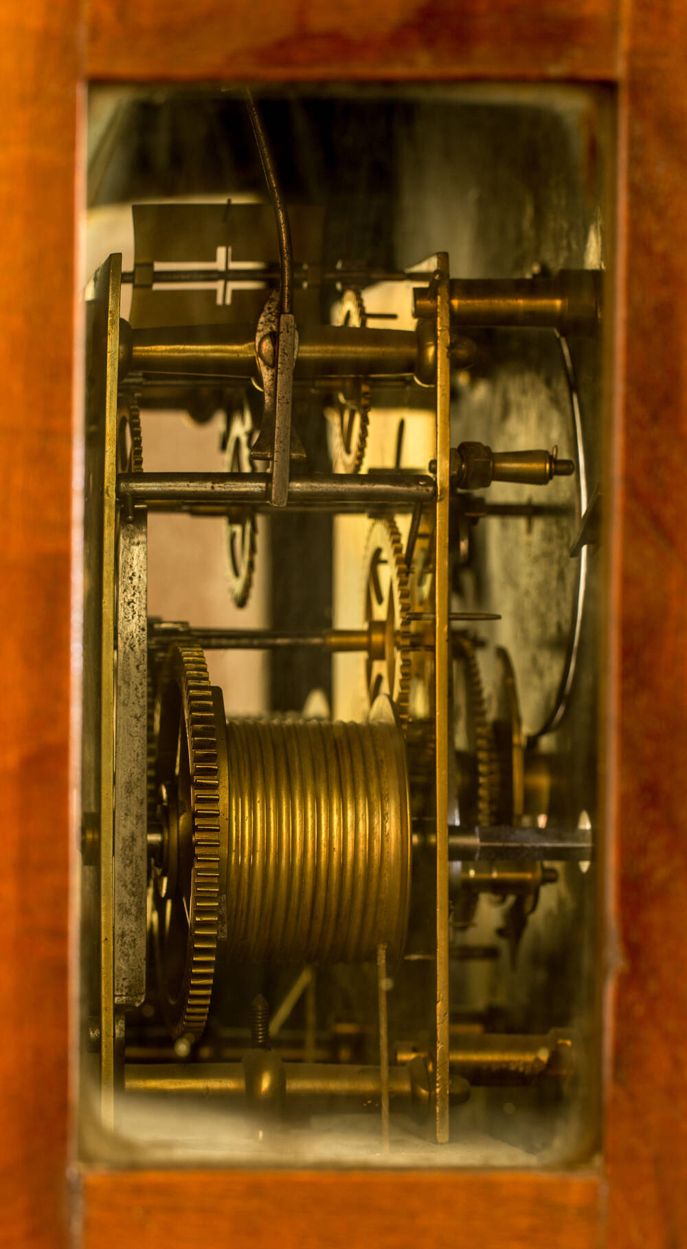 A view of a longcase clock mechanism, with coils and cogs in a wooden surround.