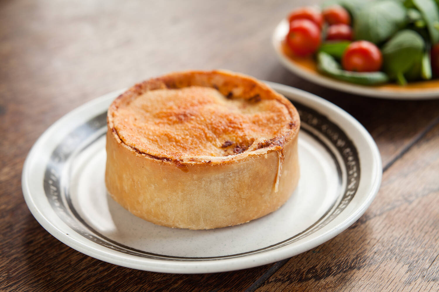 A scotch pie sitting on a small white plate 