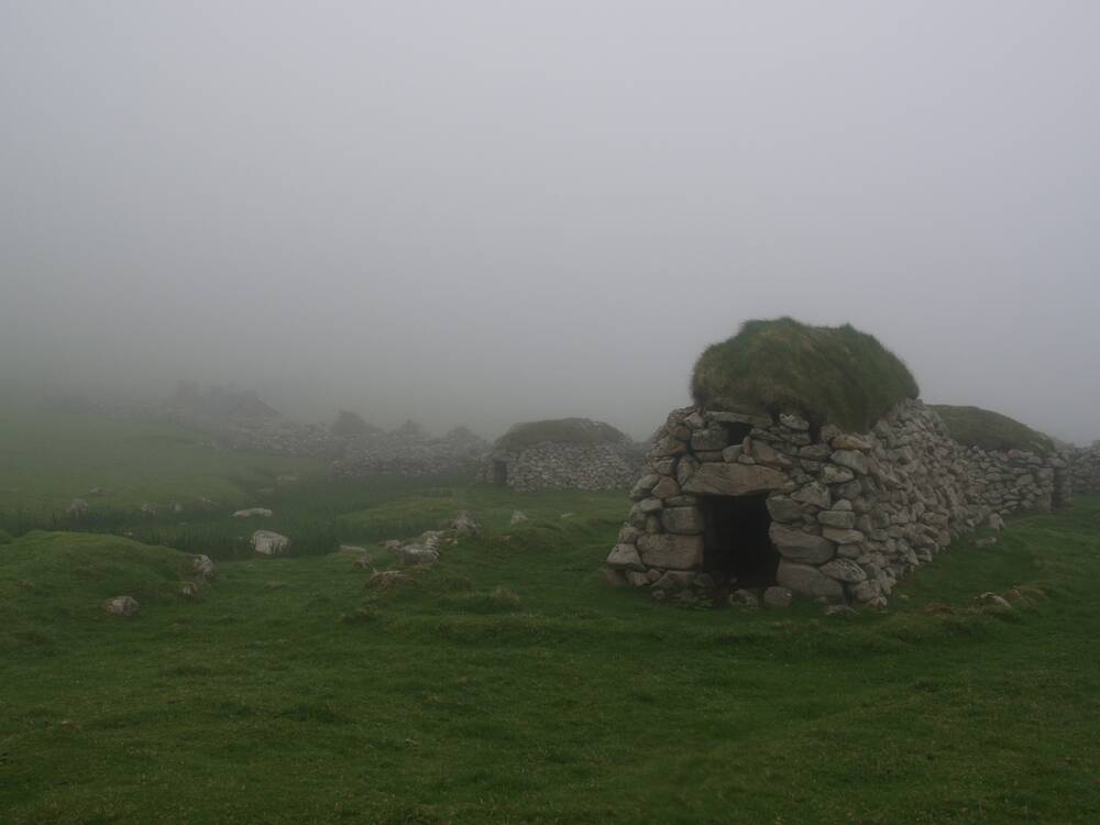 A row of cleitean on a St Kilda hillside, shrouded in mist.