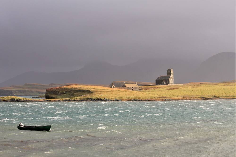 Stormy skies over an island, with a small boat in a stormy sea.
