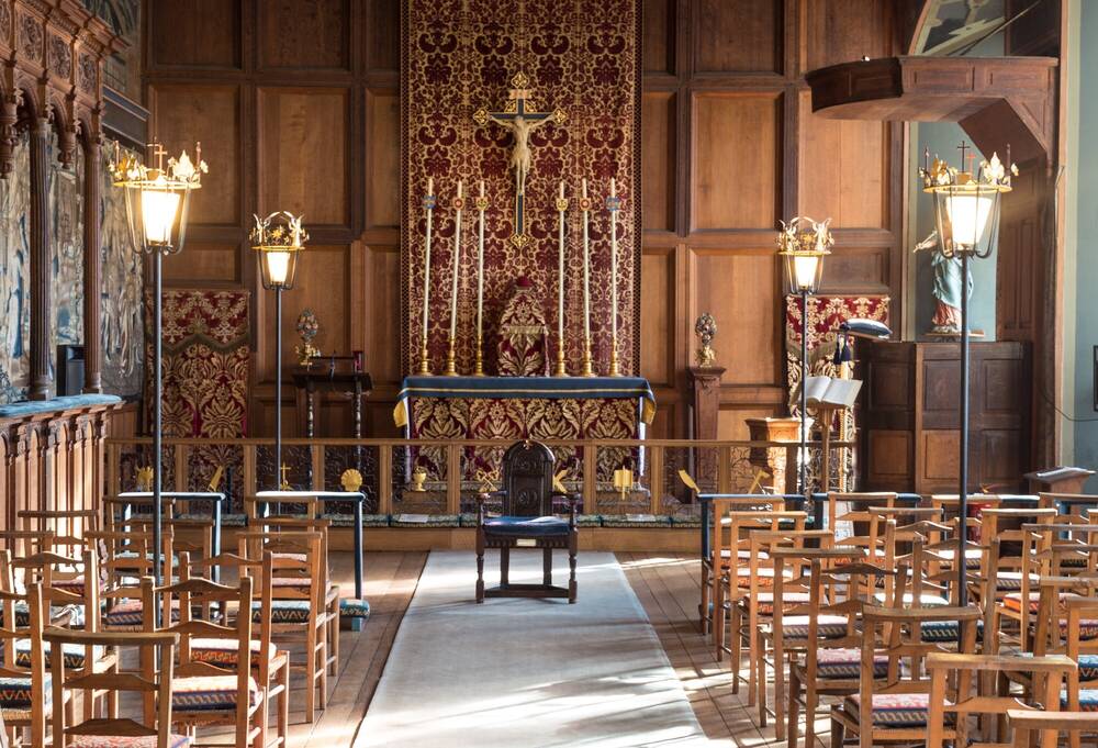 A chapel with wooden panelled walls and rows of chairs facing the altar.