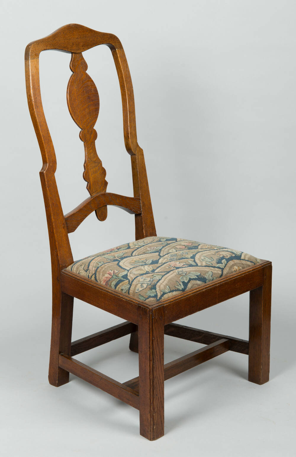 Wooden chair with padded seat, short legs and an open carved back.