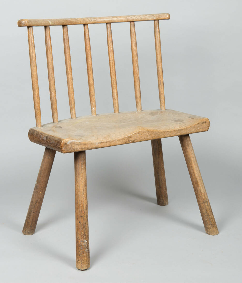 Small wooden chair with splayed legs. The back has 7 vertical struts.