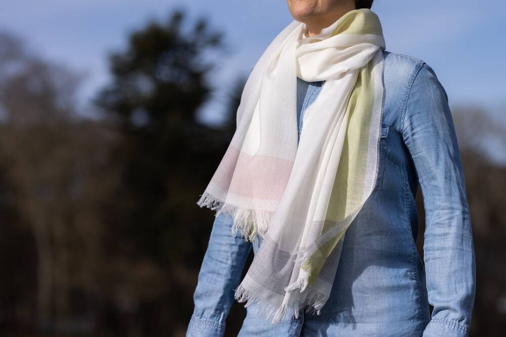 Close-up of a woman wearing a pale coloured lightweight merino scarf.