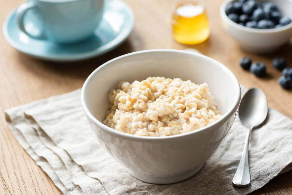 Oatmeal porridge, Scottish oats in a bowl on table, sitting on kitchen linen. 