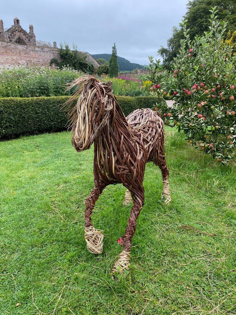 Willow sculpture of a pony in an orchard.